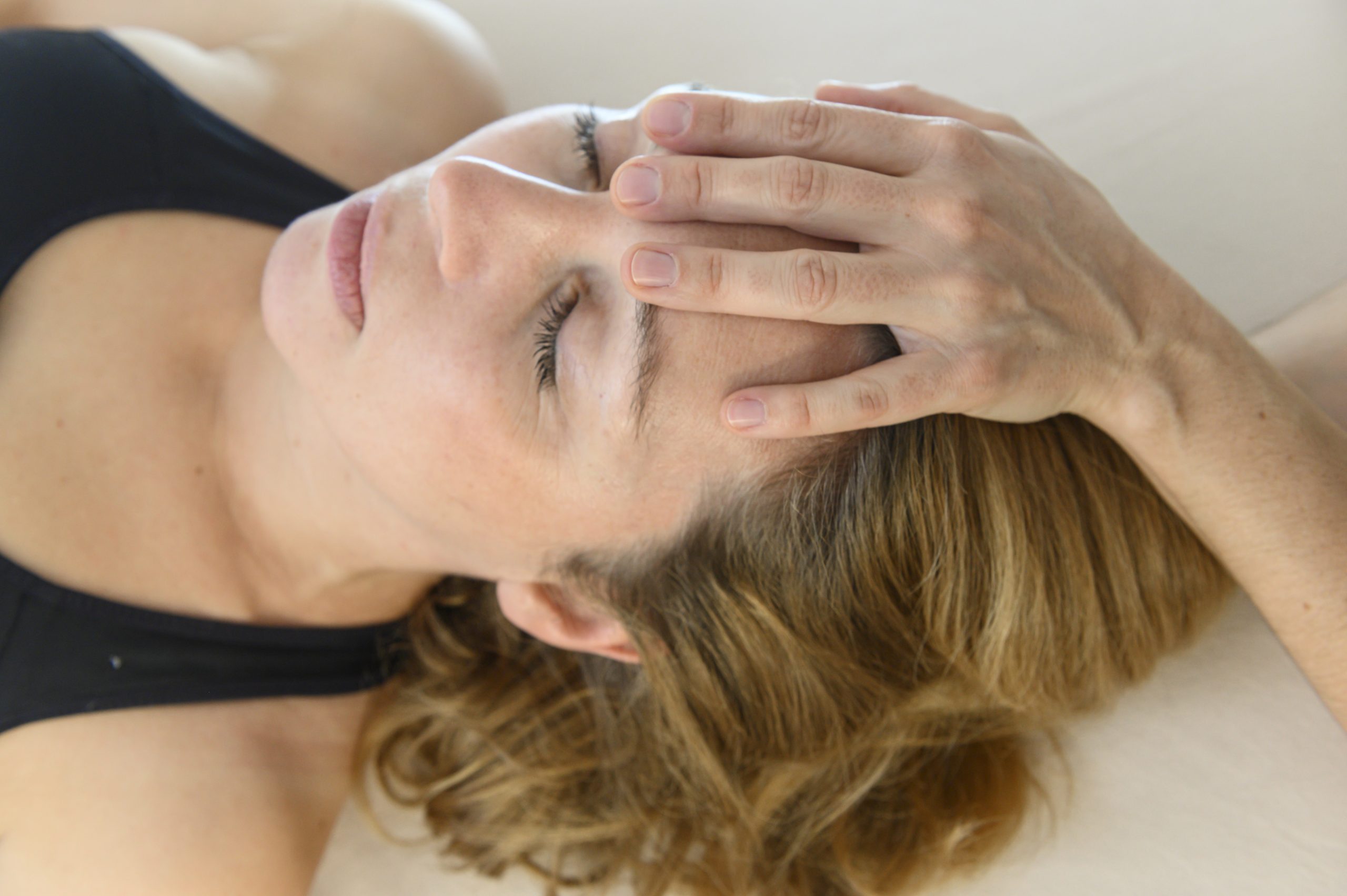 https___bv-osteopathie.de_wp-content_uploads_2020_04_DSC2782-scaled Behutsame osteopathische Behandlung einer liegenden Frau mit den Händen am Kopf